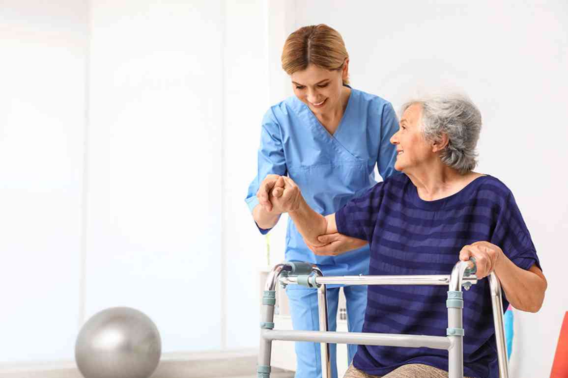 Pflegekraft hilft älterer Frau mit Gehhilfe